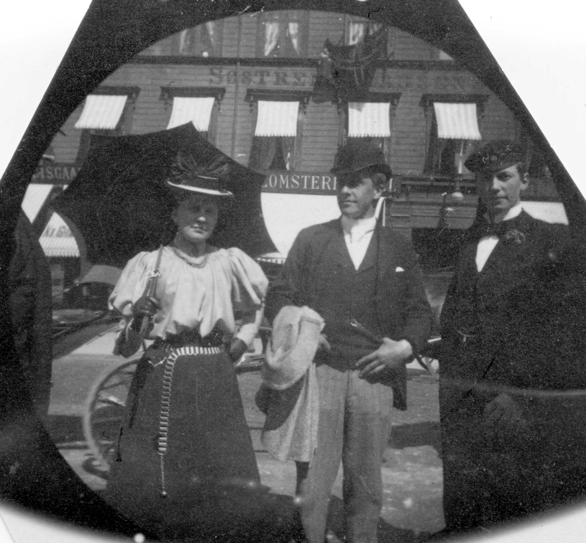 Fredrik Carl Mülertz Størmer, To menn og en kvinne står foran Søstrene Larsens Hotell på Karl Johans gate, Oslo.