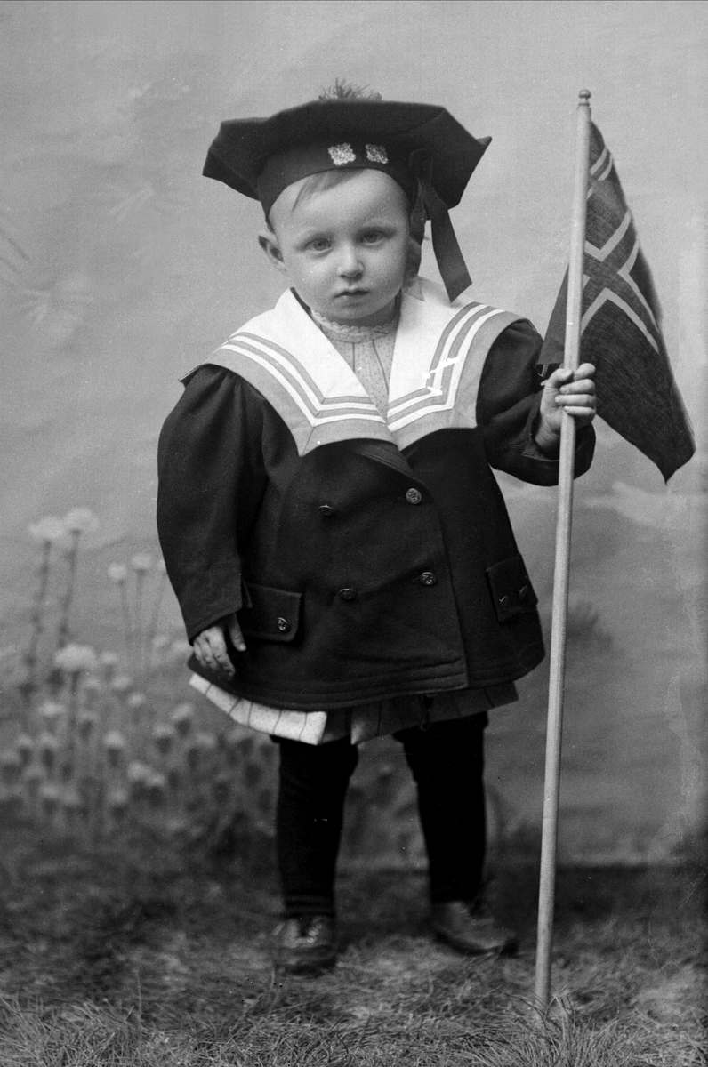 Gustav Borgen, Portrett, liten gutt i matrosdrakt med det norsk flagget. Flagget er det norsk unionsflagget (1844-1899) men de svenske fargene er fjernet. Peter Gruner.