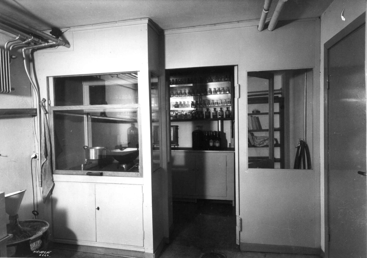 Hermann Christian Neupert, Rådhusapoteket, Oslo. 1935-1937. Analyserom sett fra laboratoriet. Hyller med flasker.