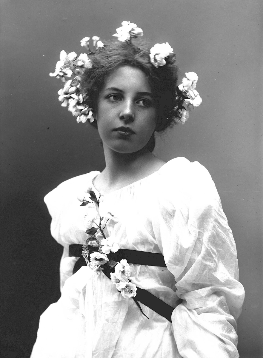 Solveig Lund, Studioportrett av kvinne i drakt med blomster i håret.