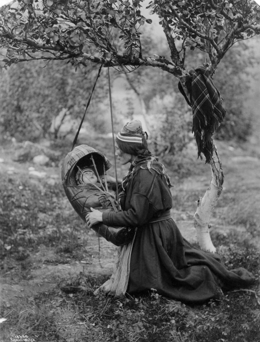 Anders Beer Wilse, Samekone med barn i komse som henger i en gren. Lappland 1916.