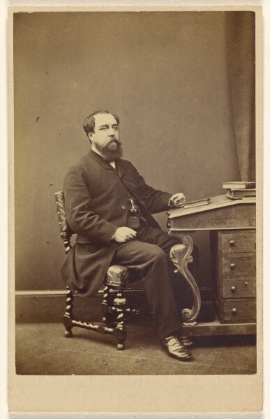 London Stereoscopic and Photographic Company, [Unidentified bearded man seated at writing desk, in 3/4 profile]