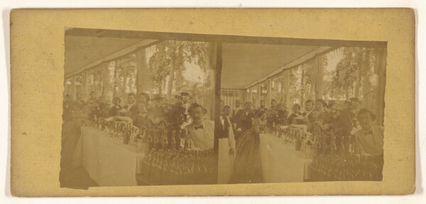 Unknown, [People posed around a table filled with champagne and other bottle of wines, etc.]