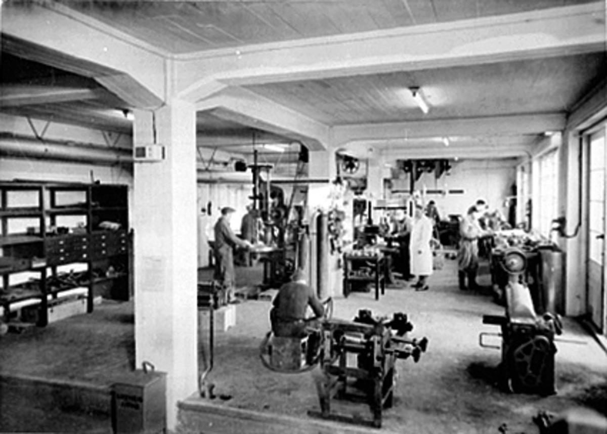 Anno Domkirkeodden, INTERIØR VERKSTEDET. 7 MANN I ARBEID, E. NORDBY MED HVIT FRAKK, DYRE WETHAMMER TIL VENSTRE OG TORBJØRN VOLD TIL HØYRE, IDEAL FLATBRØDFABRIKK A/S