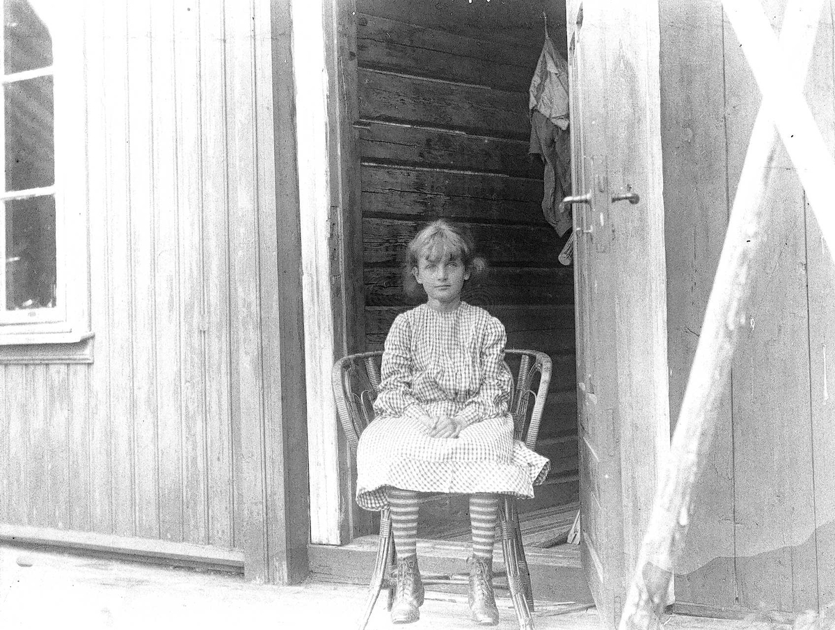 Axel Quinsgaard Wiborg, Holoa seter, Hadeland, Jevnaker, Oppland, 1903. Karen Q. Wiborg sitter på stol i døråpning.