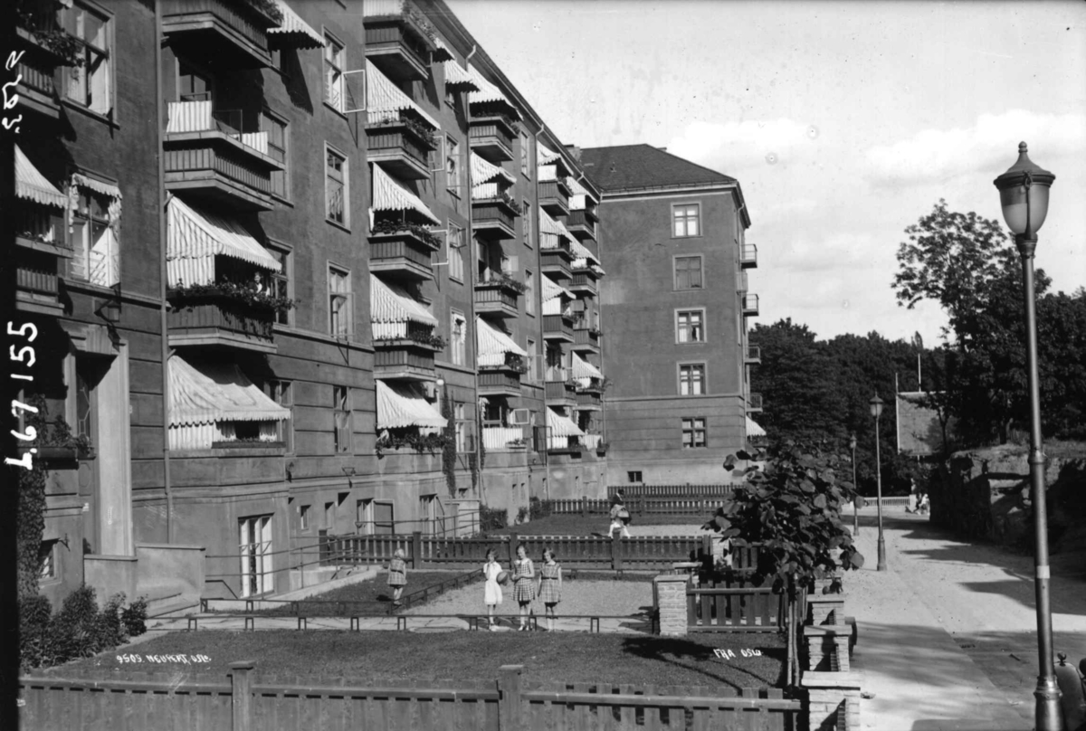 Hermann Christian Neupert, Oslo. Fire jenter i forhagen til bygård med verandaer og markiser.