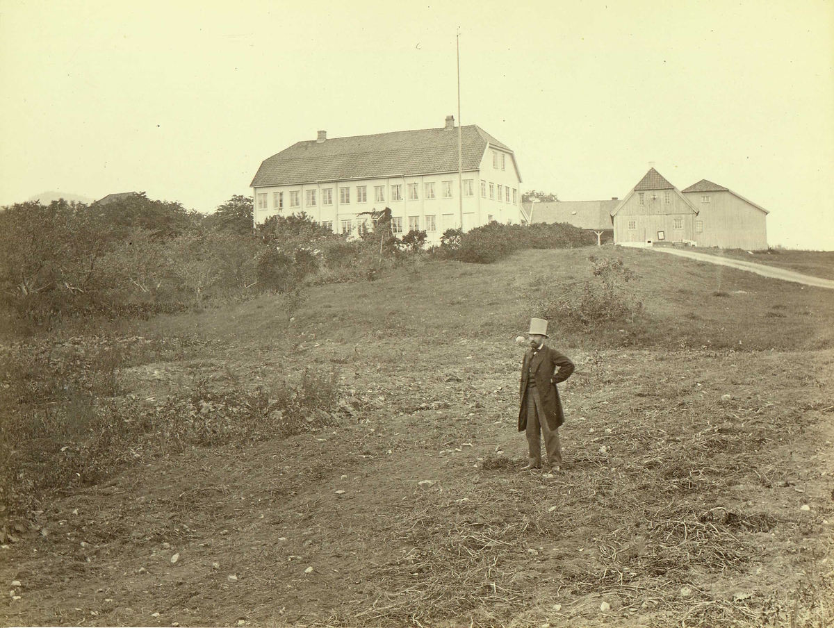 Henry Rosling, Ris hovedgård i Oslo. Mann i flosshatt poserer foran stor hovedbygning med uthus omkring.. Fra serie norske landskapsfotografier tatt av den engelske fotografen Henry Rosling (1828-1911).