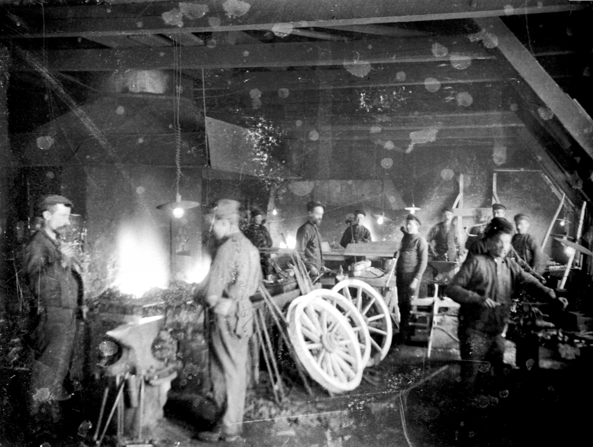 Anno Domkirkeodden, Interiør, smia på Moelven Brug. 11 mann i arbeid med produksjon av kjerrehjul. Smed.