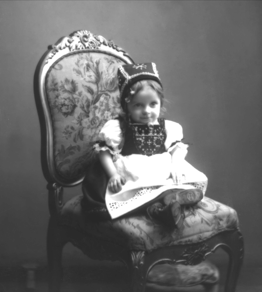 Gustav Borgen, Portrett, liten pike på stol, i hardangerbunad. Fuglesangs datter.