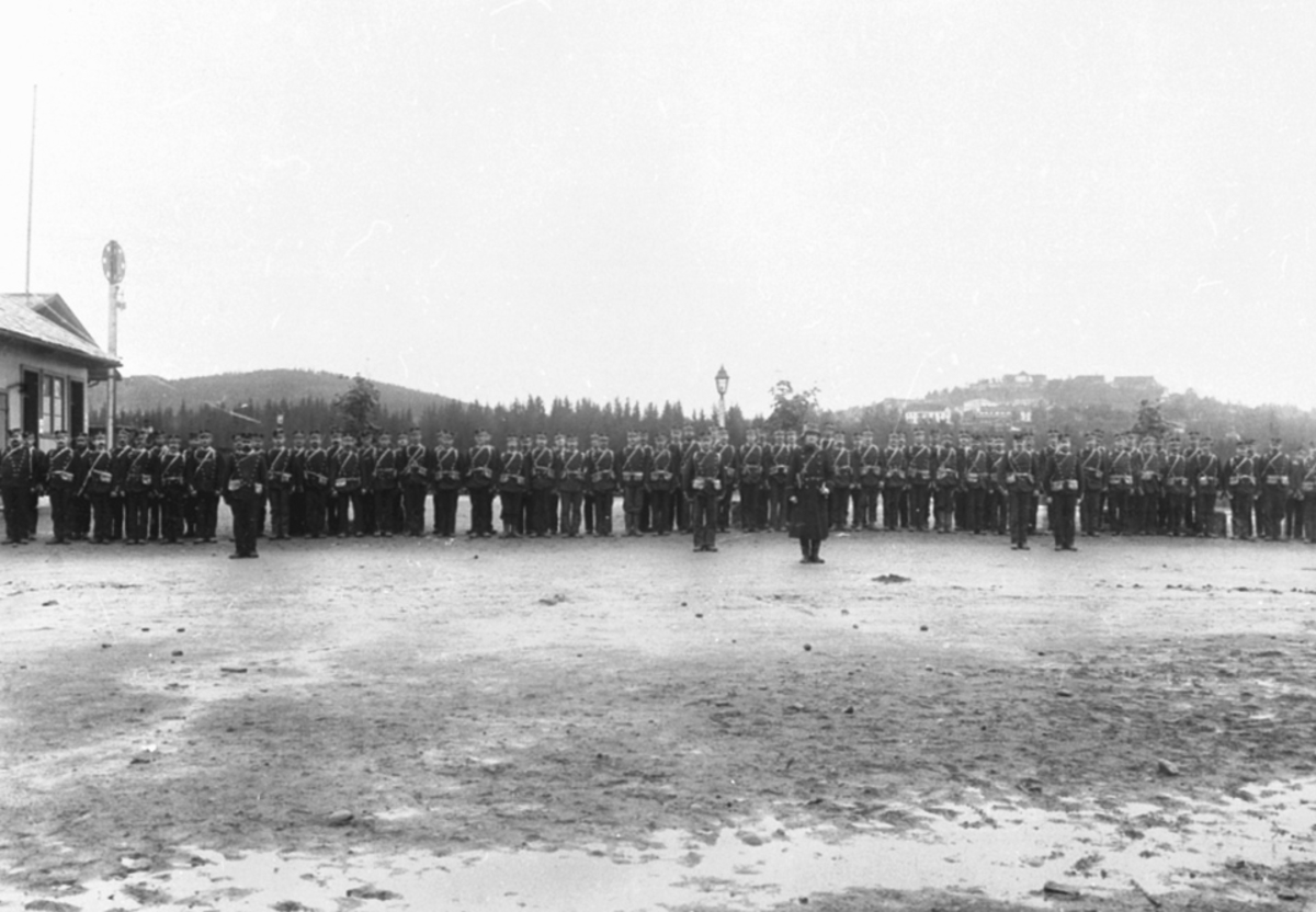 Anno Domkirkeodden, KONGSVINGER FESTNING, SOLDATER OPPSTILT, MOBILISERING I 1905, NR. 2. FRA VENSTRE: LØITNANT NILS STENBERG. Kongsvinger festning i bakgrunnen. Soldatene er antagelig stilt opp nede ved jernbanen på Glommas sørside.