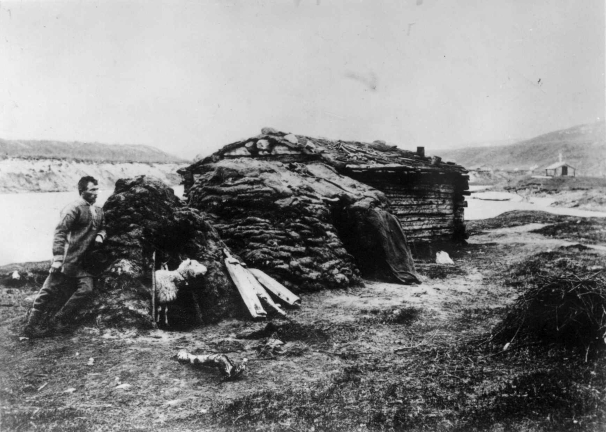 Ellisif Rannveig Wessel, Skoltesamisk hus med fegamme, Neiden, Sør-Varanger, Finnmark, ca. 1905. Mannen utenfor er Miket Ivanowetsj (1876-1916).
