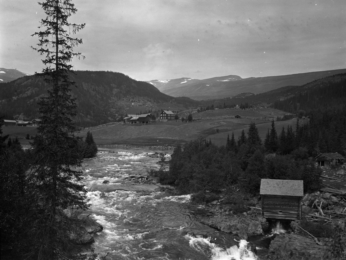 Kristian Heramb, Valdres, Vestre Slidre i Oppland. Thorpegardane i Vang i Valdres. Garden Rogn i framgrunnen. Belsheimgardane ligg under Belsheimberget i bakgrunnen, kvernhus,