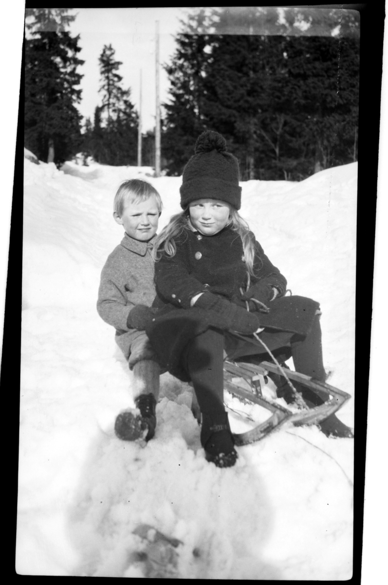 Rolf Sr. Sundt, Julius Sundt sitter på kjelke sammen med en litt eldre ukjent jente, Villa Knyggen. Fotografert 1922.