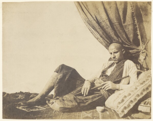 Unknown, [Reclining Algerian man with pipe]