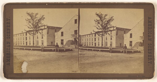 Unknown, Hudson River. [Two men sitting on a railing outside a large building complex]