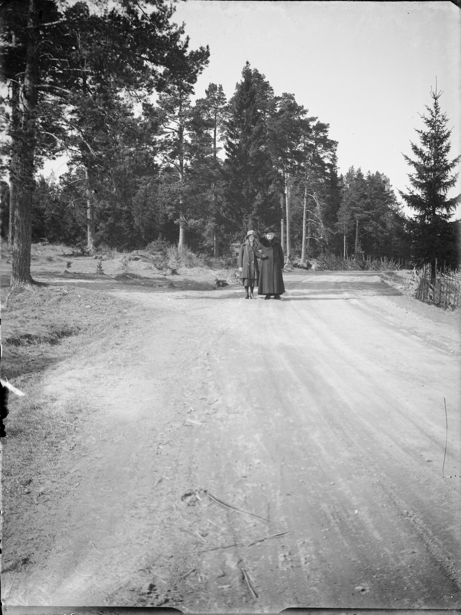 Skötsner-Edhlund, Brita and Tyra Edhlund stand on the road, Östhammar, Uppland