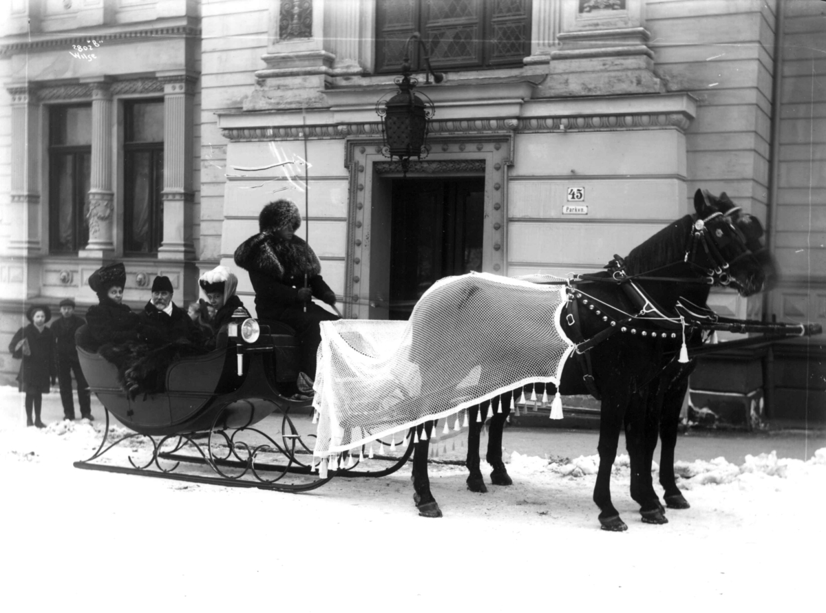 Anders Beer Wilse, Utenriksminister Wilhelm Christophersen, hans kone og trolig datter i slede, Victoria-sluffe og hester med sledenett, utenfor utenriksministerboligen i Parkveien 45 i Oslo. Vinter og snø.