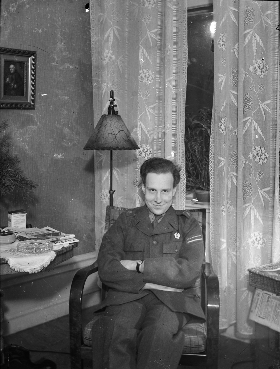 Okänd,, Ung man i militäruniform sitter i fåtölj, sannolikt i hemmet, Sverige