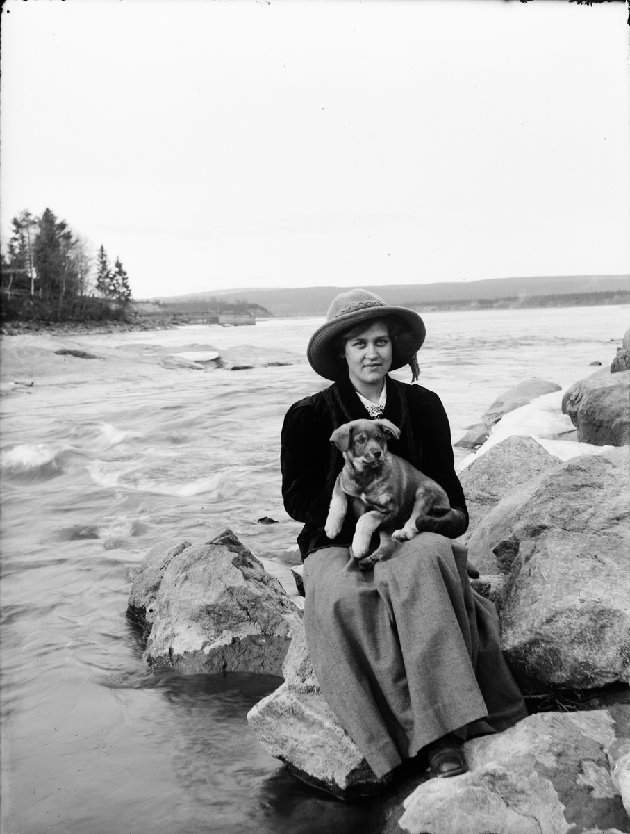 Josef Ärnström, Naima D-n med hundvalp vid älven 1911, sannolikt Berge, Timrå socken, Medelpad