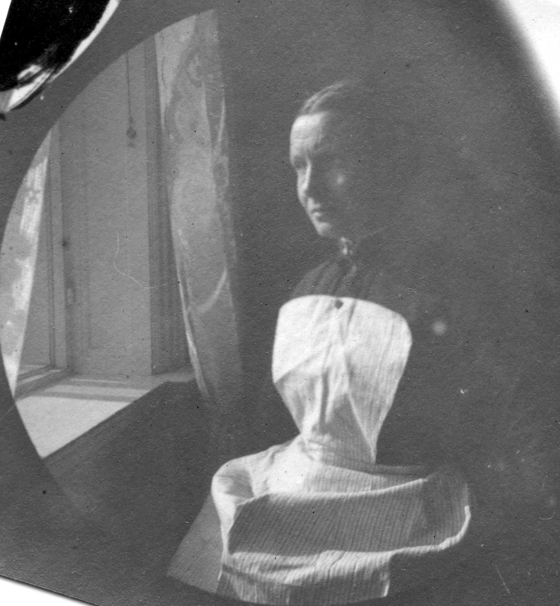 Fredrik Carl Mülertz Størmer, Beathe Larsen, kokkepike hos apoteker Størmer, med hvitt forkle, sitter ved vindu.