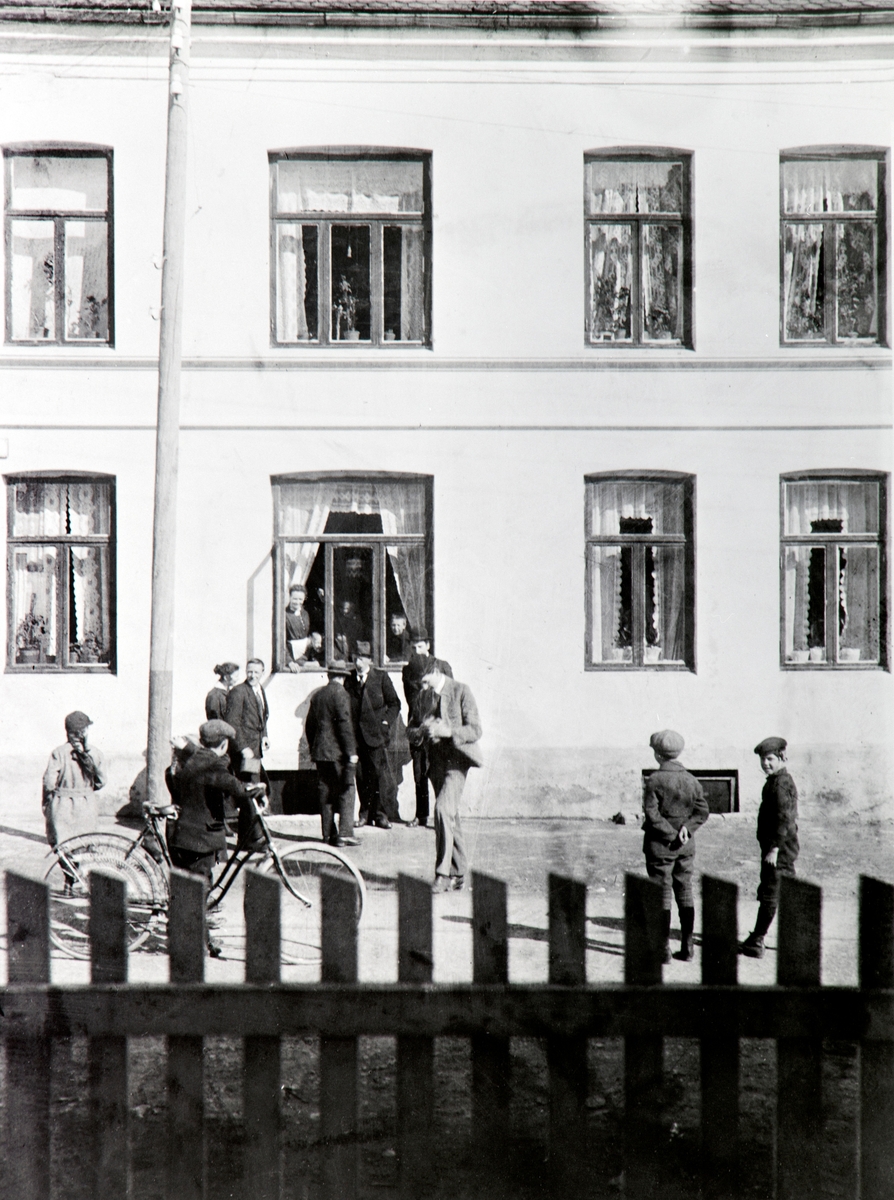 Anno Domkirkeodden, HYGGELIG PRAT MELLOM NABOER I OLE BULLSGATE, FRA VENSTRE ASTRID AASEN, KAARE NORDERHAUG MED SYKKEL, JOHAN ANDERSEN TIL VENSTRE FOR VINDUET, ADOLF ANDERSEN MED RYGGEN MOT FOTOGRAFEN, PAULI ANDERSEN, STASJONSFORMANN, STÅR RETT UNDER VINDUET. I VINDUET FRA VENSTRE MINA ANDERSEN OG FREDRIK NDERSEN, LEN…