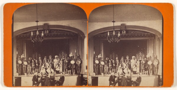 Unknown, [Actors posed on stage, three-piece musical group at center bottom]