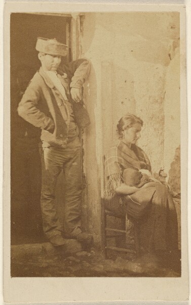 Unknown, [Man standing next to a seated woman holding a baby]